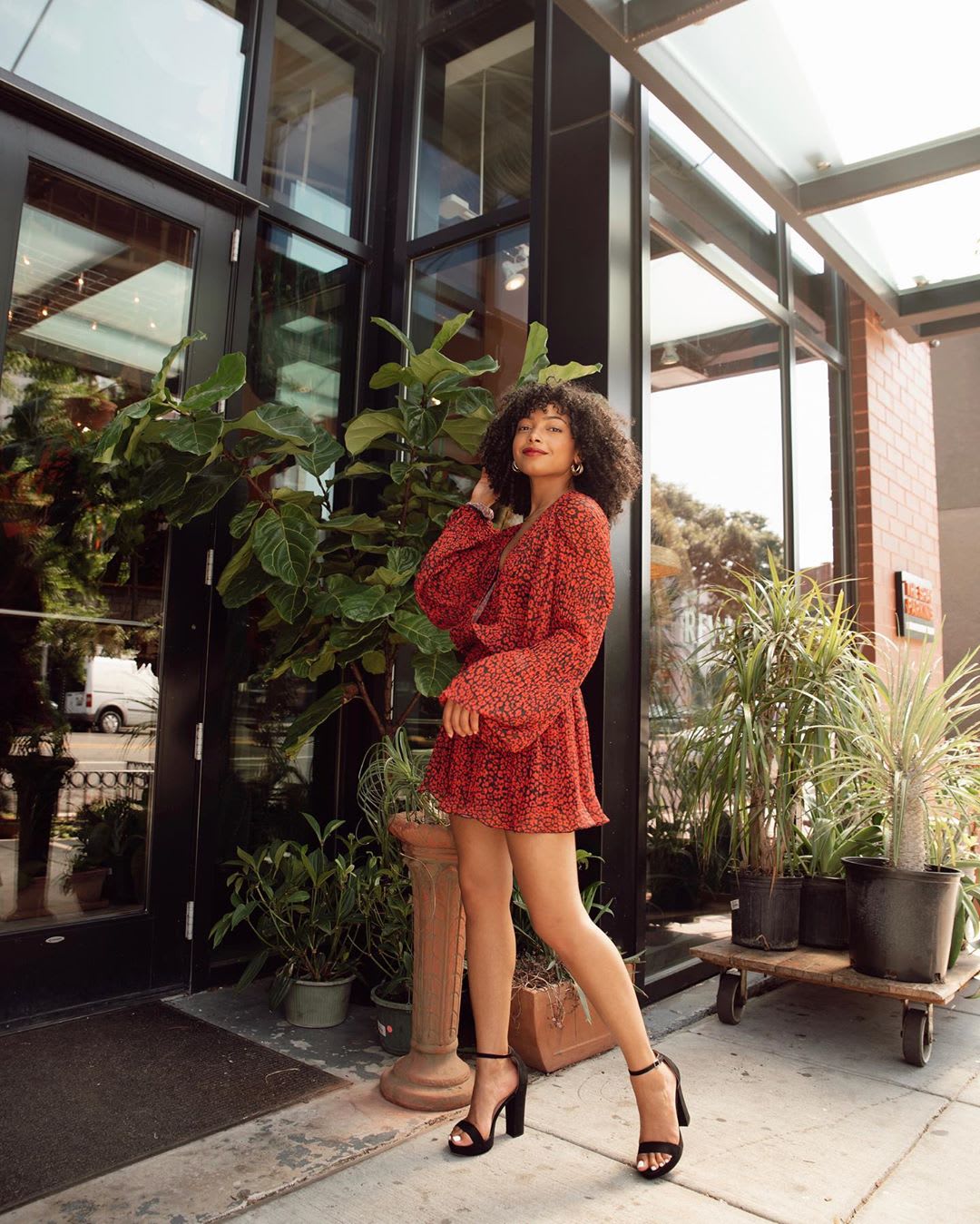 woman in red dress in front of outdoor plants