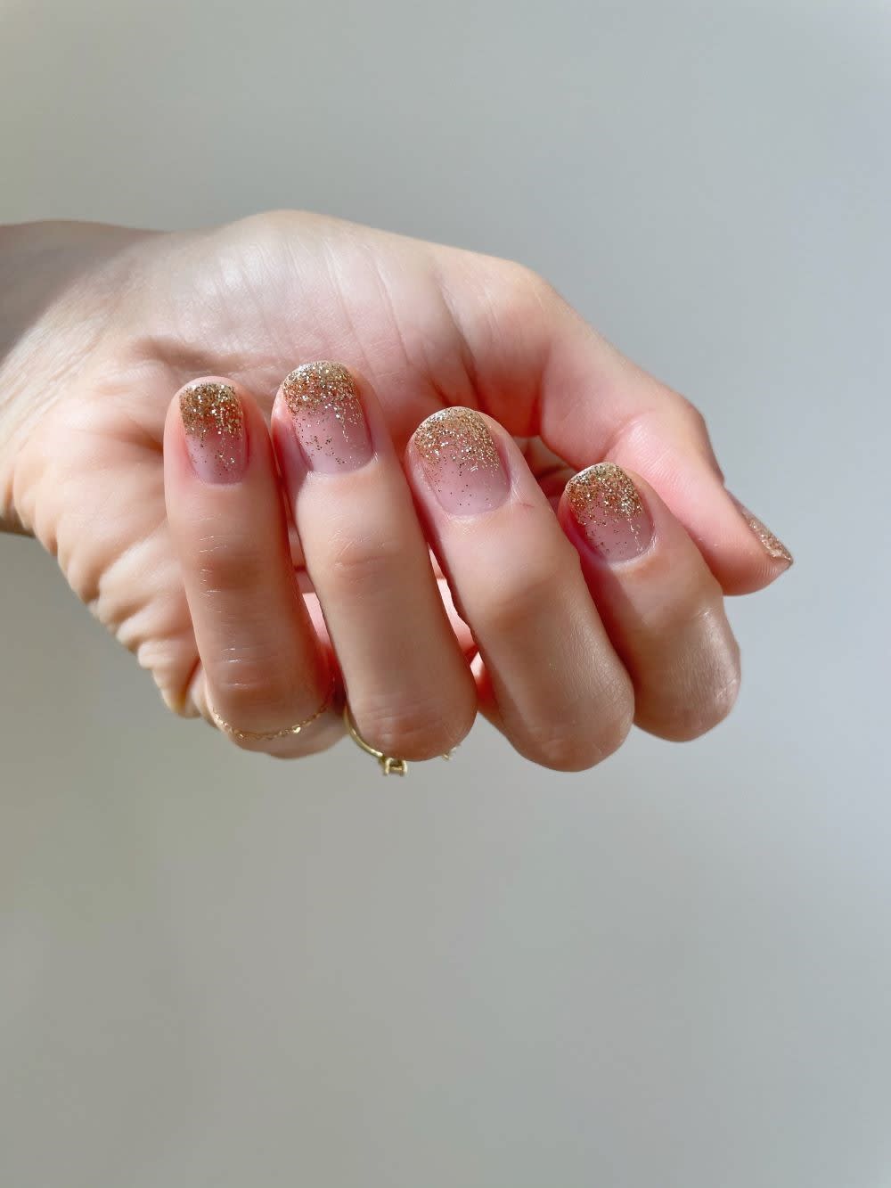 a folded hand with gold glitter gradient nails