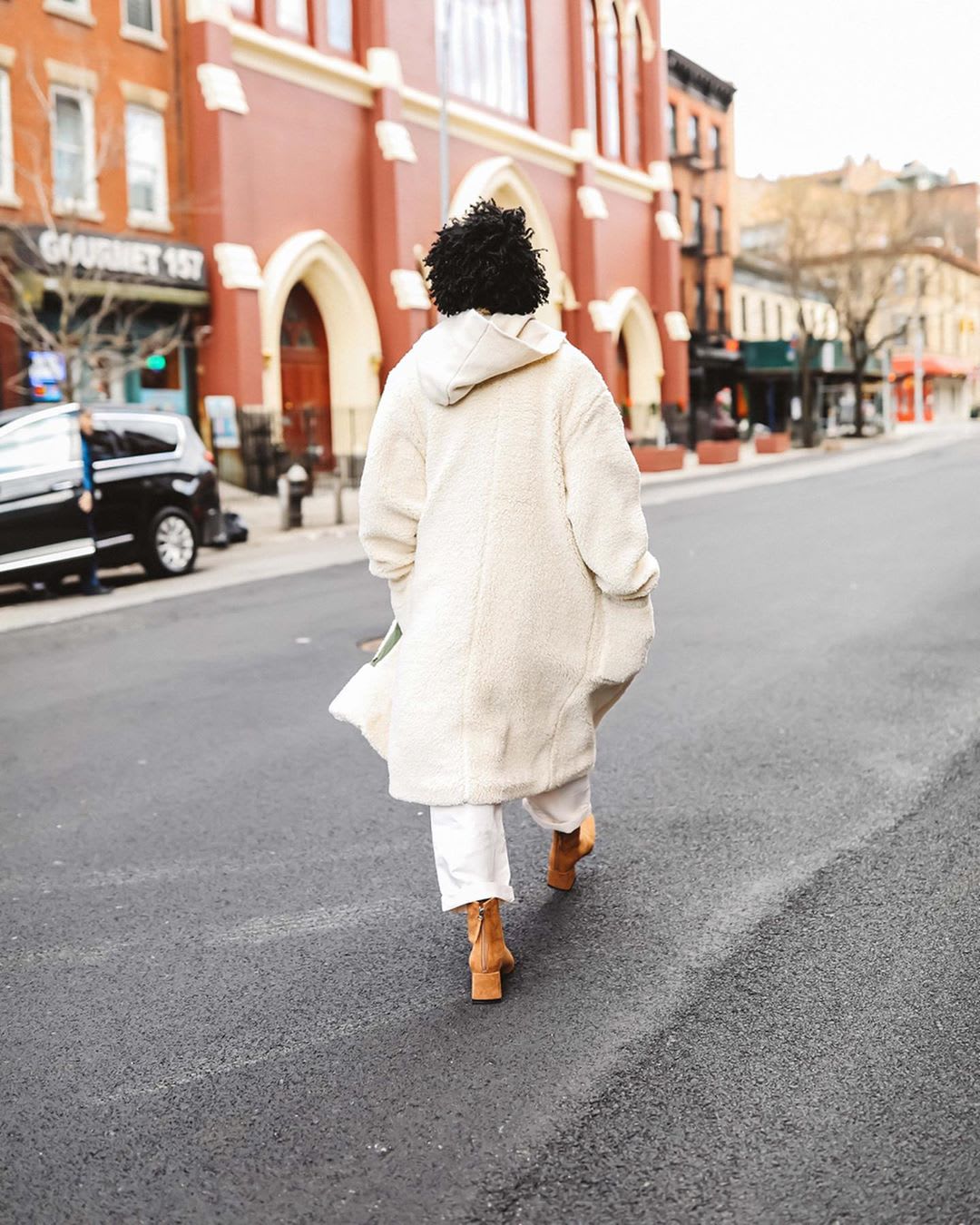 woman walking down the street in cream coat