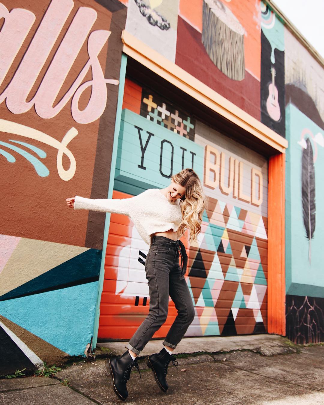 woman jumping in front of a wall mural