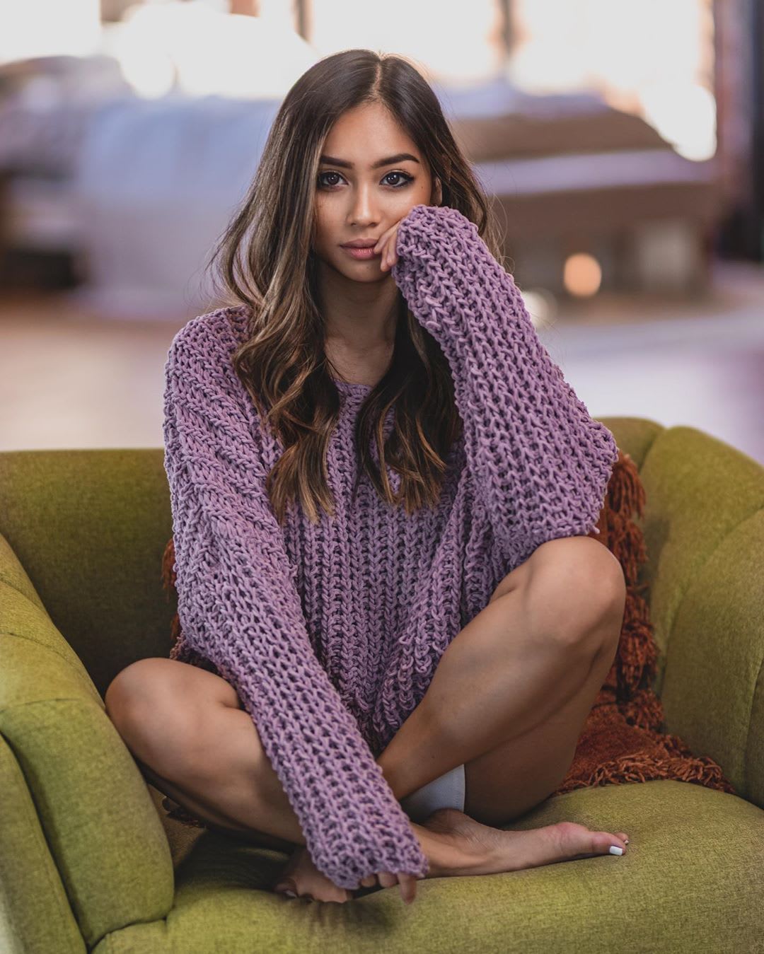 woman in a purple sweater on an armchair at home