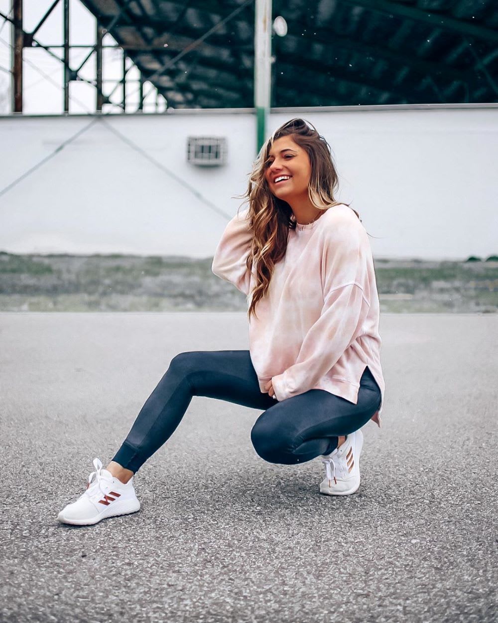 woman in tie dye shirty and leggings doing a workout