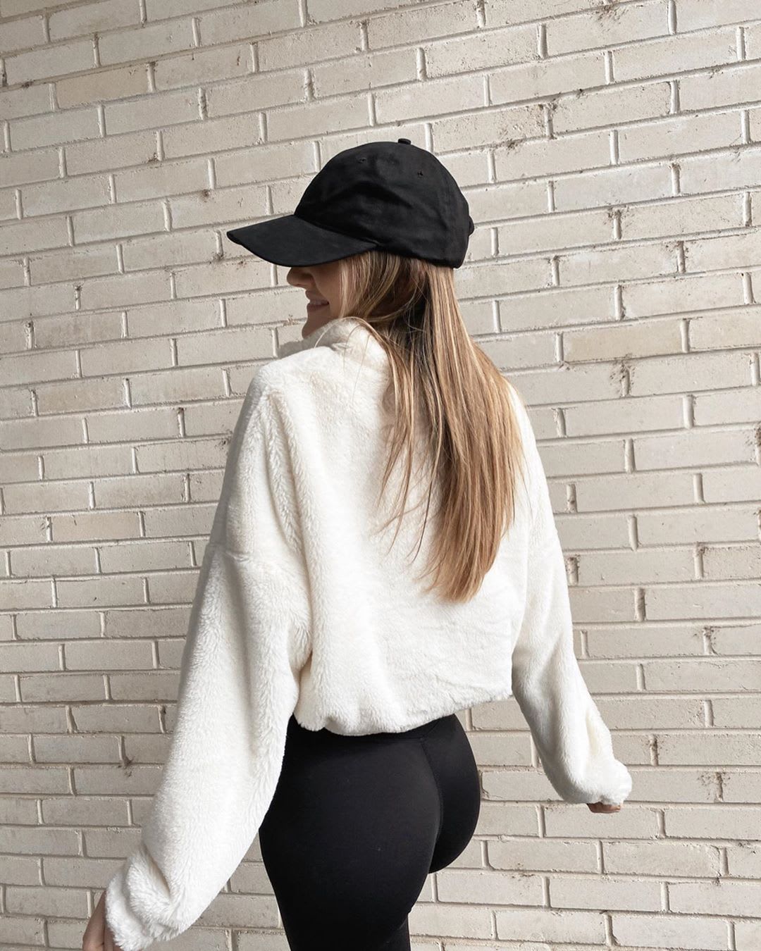 woman in leggings and baseball cap and pullover