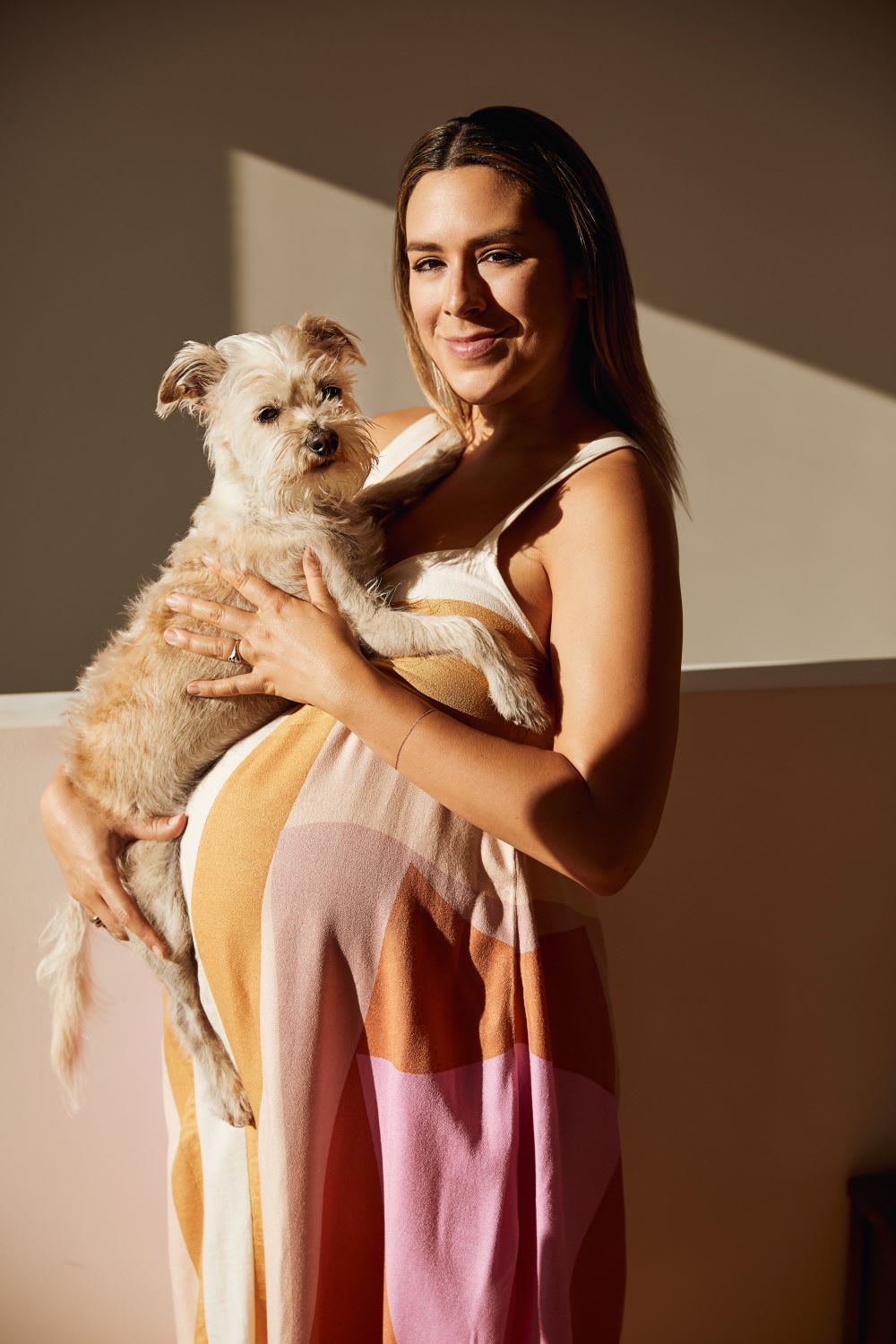 pregnant woman in summer maternity clothes holding a dog
