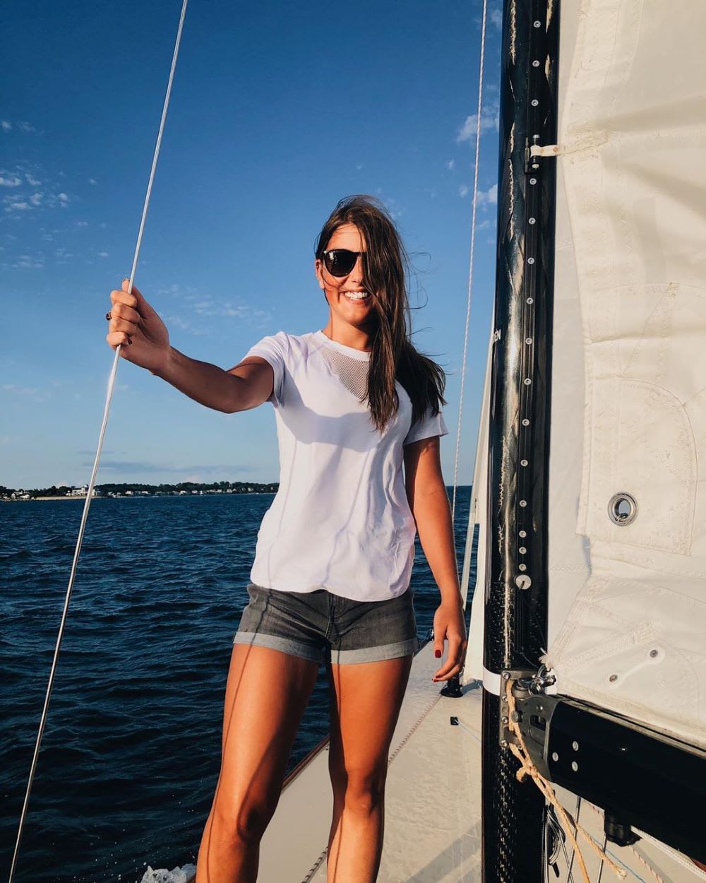 woman in a white tee and denim shorts on a boat