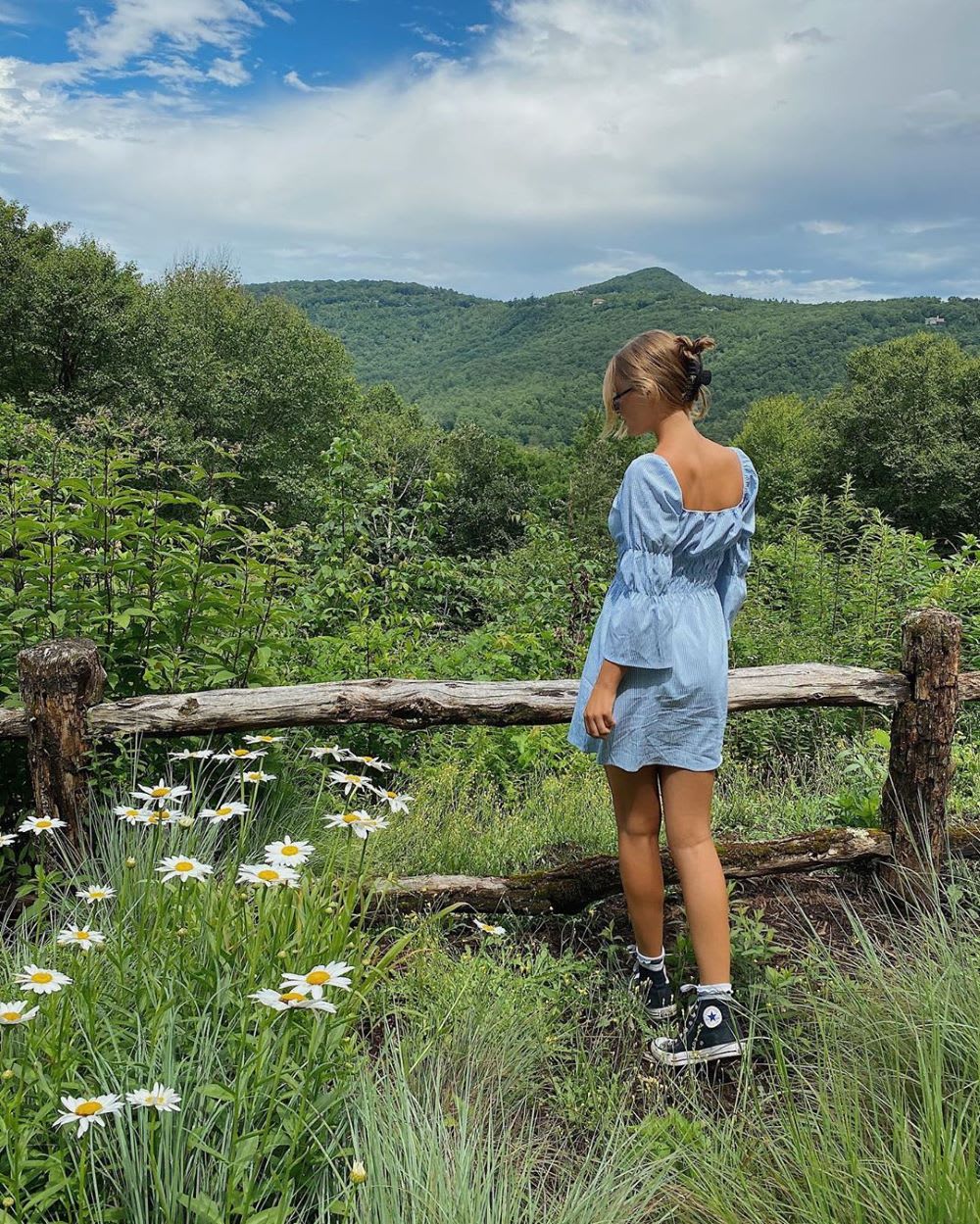 woman in a denim dress overlooking outdoors forest like on an RV trip