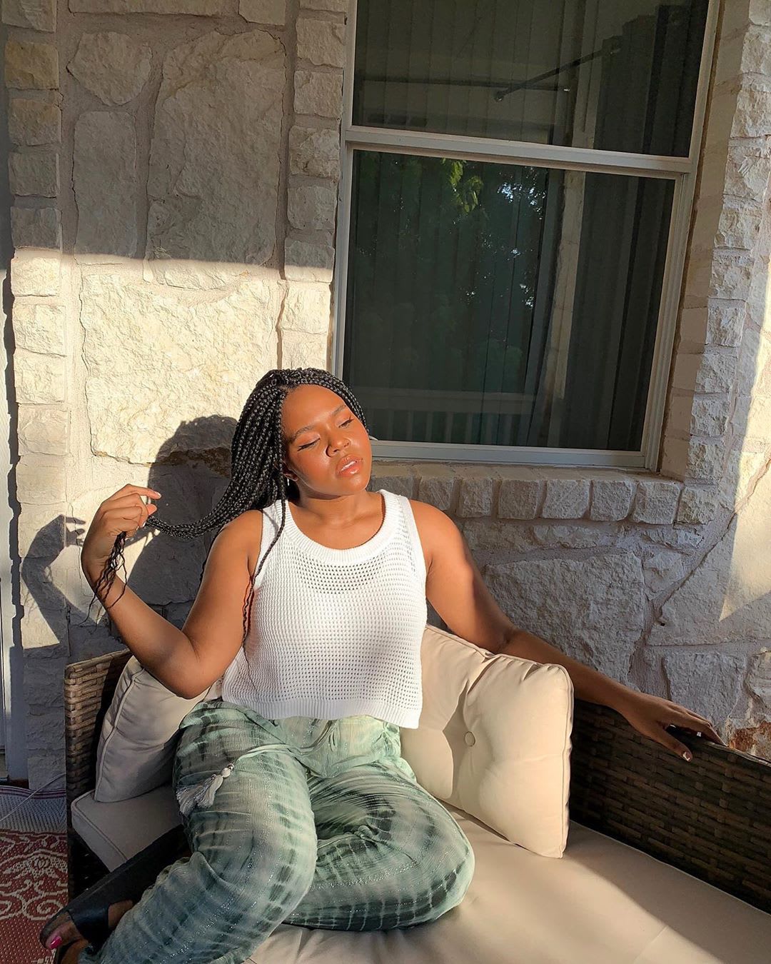 woman wearing a white knit tank and tie dye pants in the sun