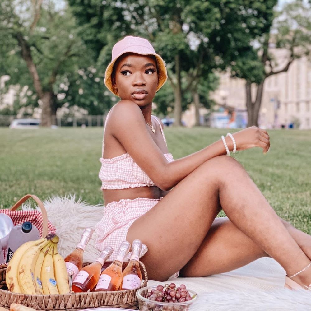 woman in the park wearing a gingham two piece romper in pink