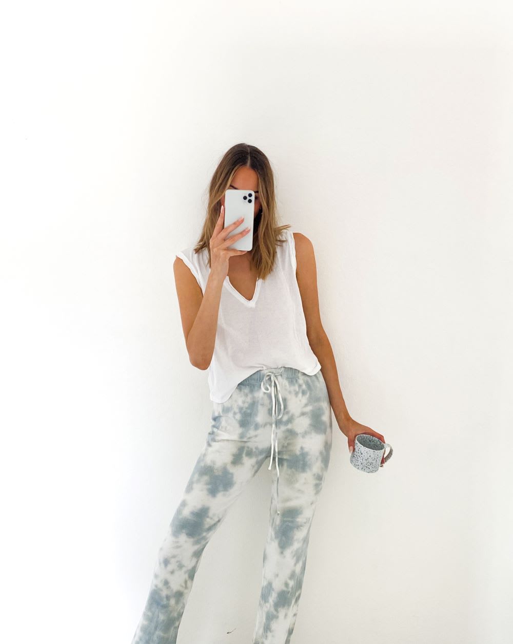 woman wearing a sleeveless white tee and tie dye joggers