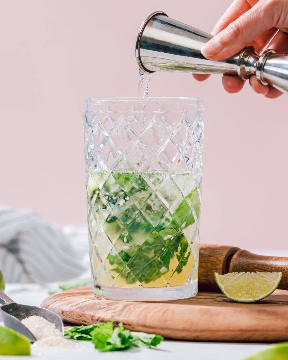 hand mixing a cucumber mojito in a glass