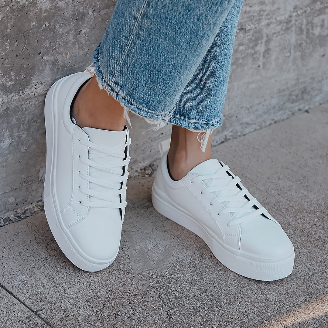 hems of jeans and feet wearing white platform sneakers