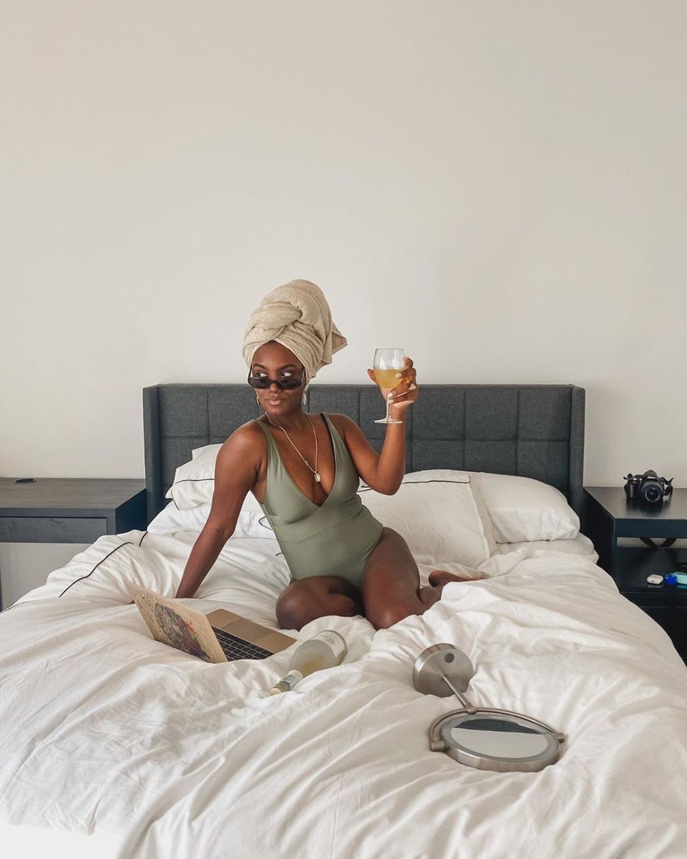 woman taking a workcation in a bathing suit and towel on her head drinking wine at a computer
