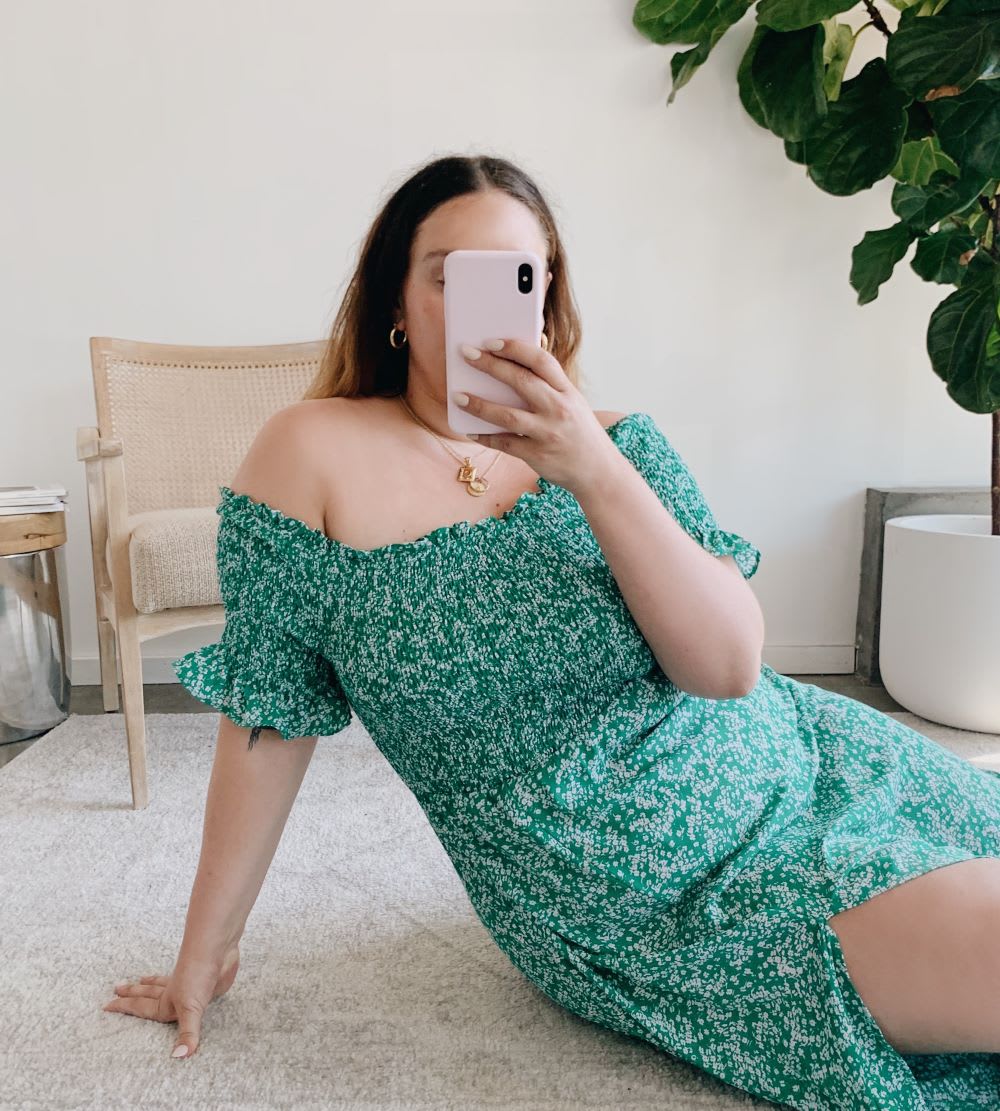 woman in a green smocked dress taking a selfie on the floor