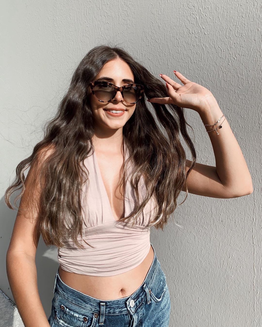 woman wearing sunglasses and halter top flipping her long hair