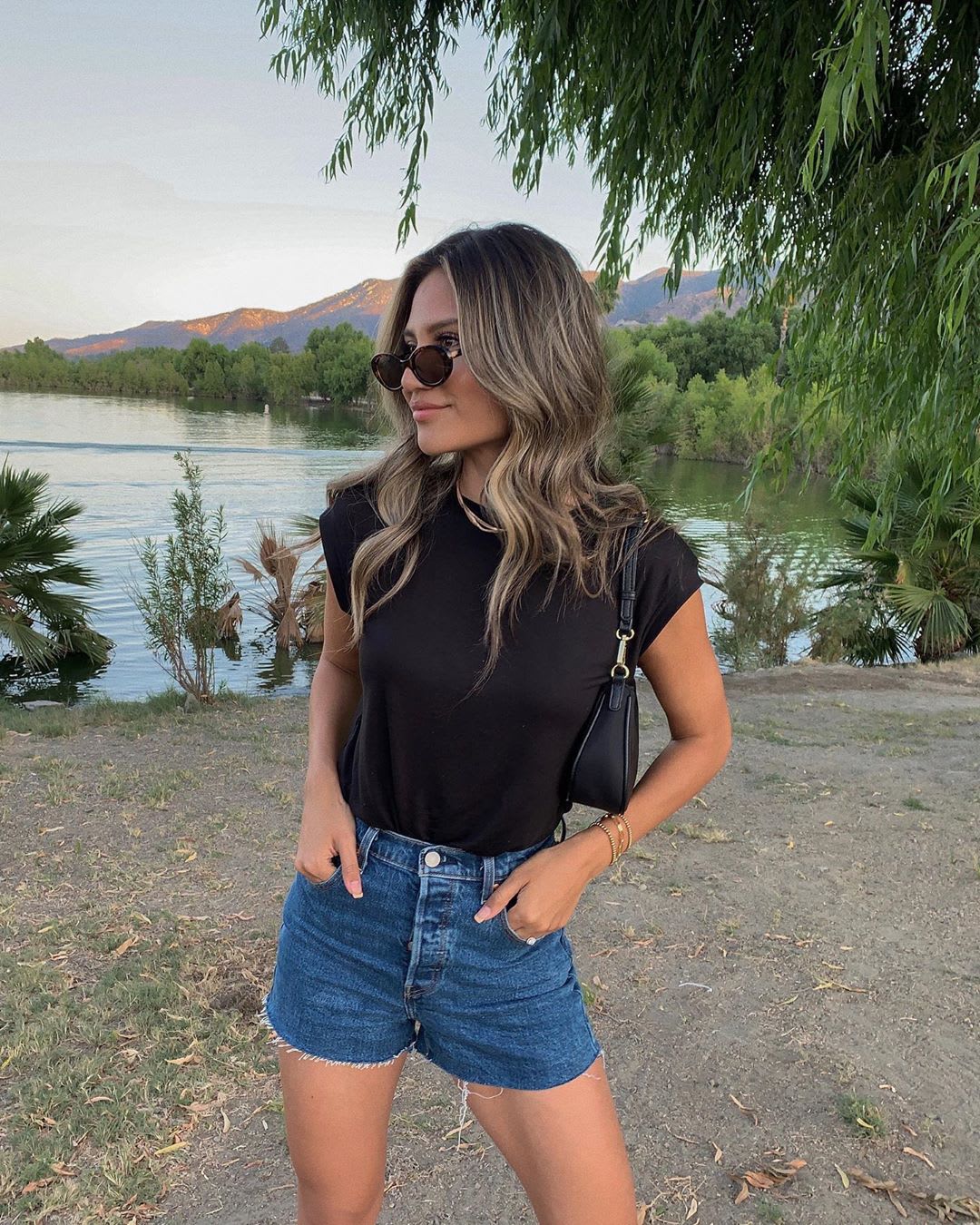 woman standing by a lake in denim shorts