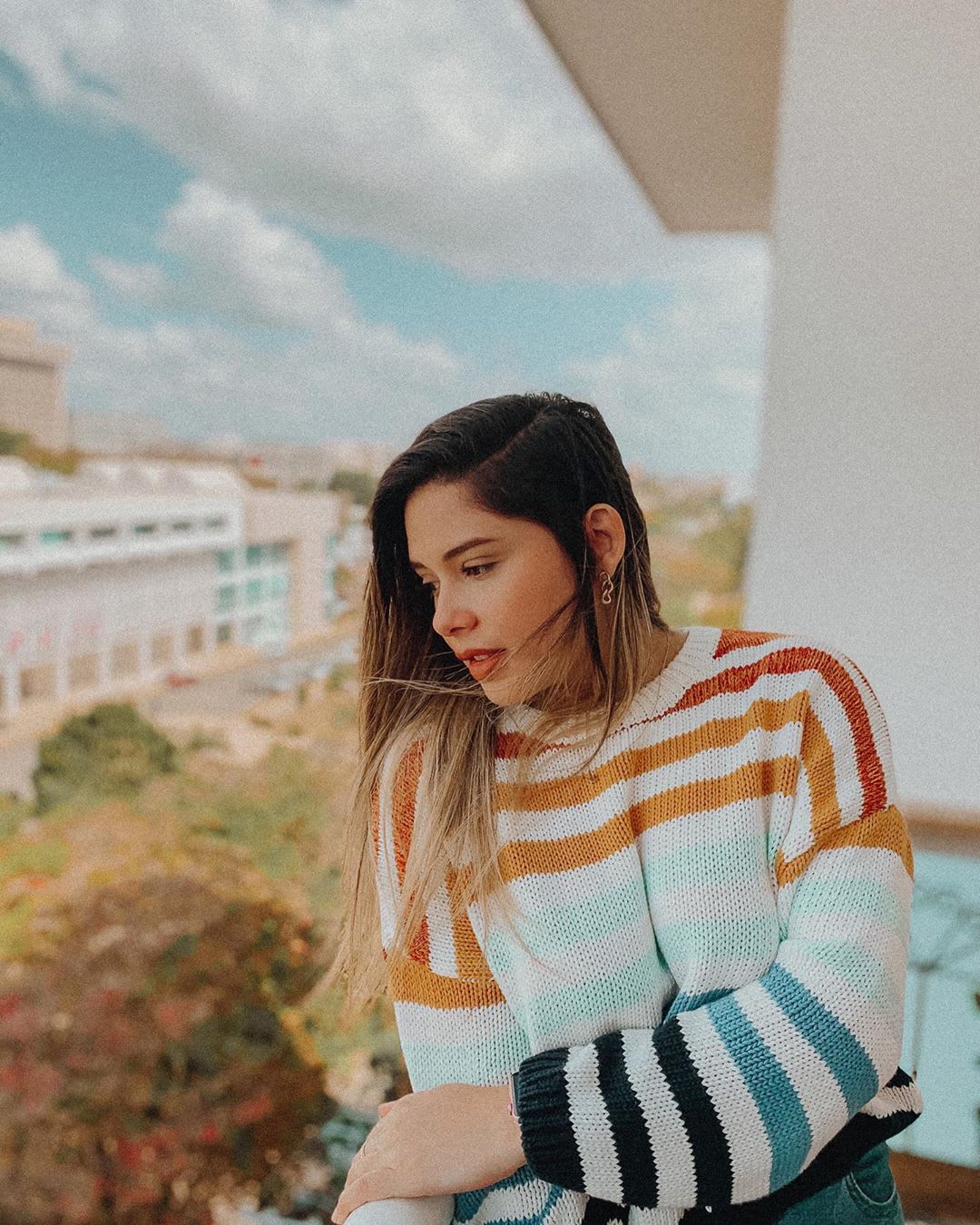 woman in a striped sweater looking off a balcony