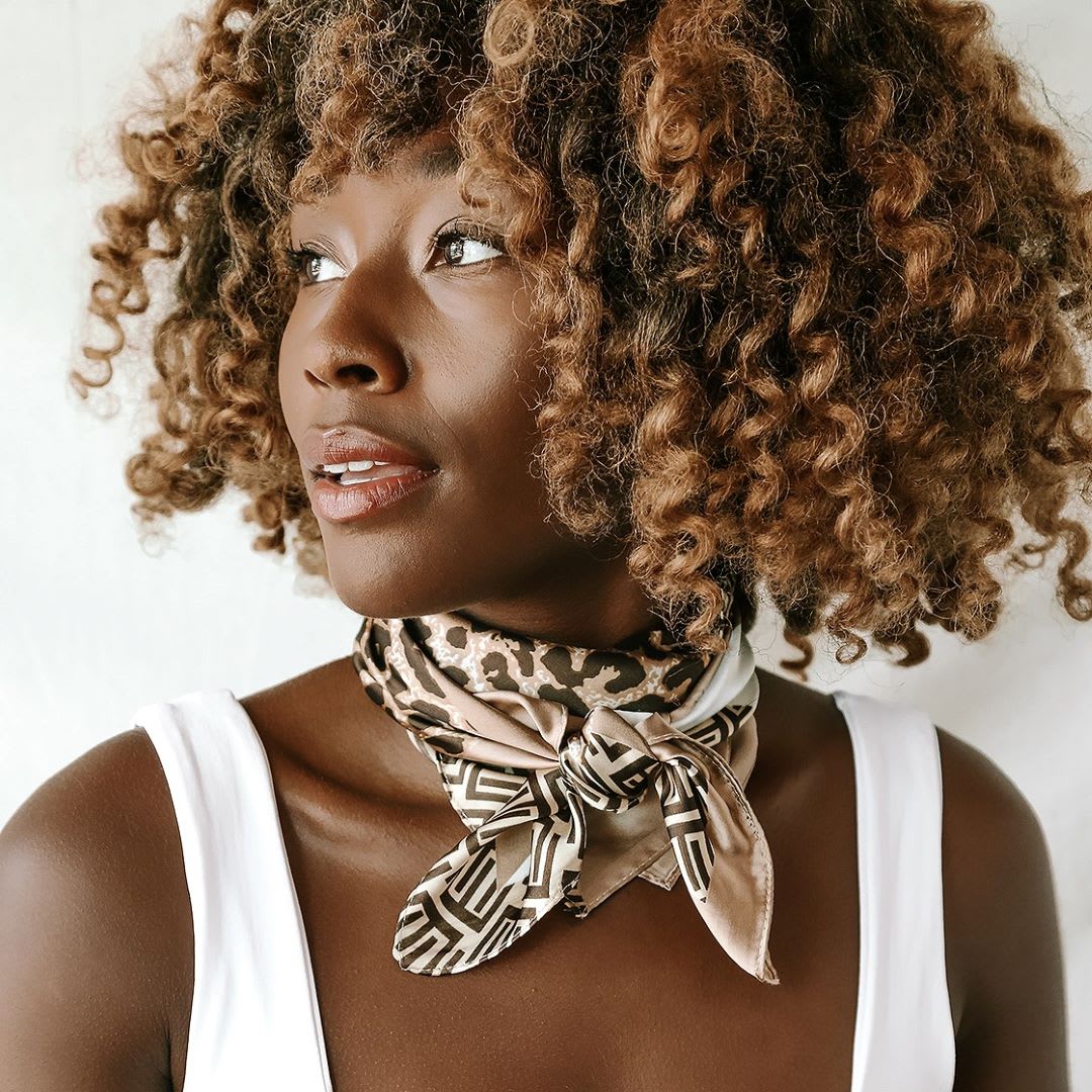 a woman in a white tank top with a leopard hair scarf worn as a neckerchief