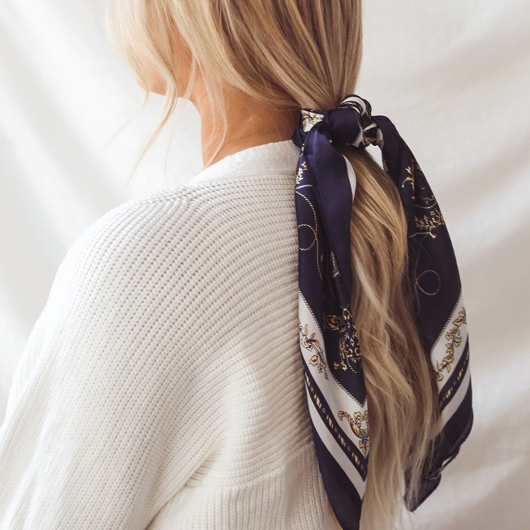 blonde ponytail with a navy striped hair scarf tied around it