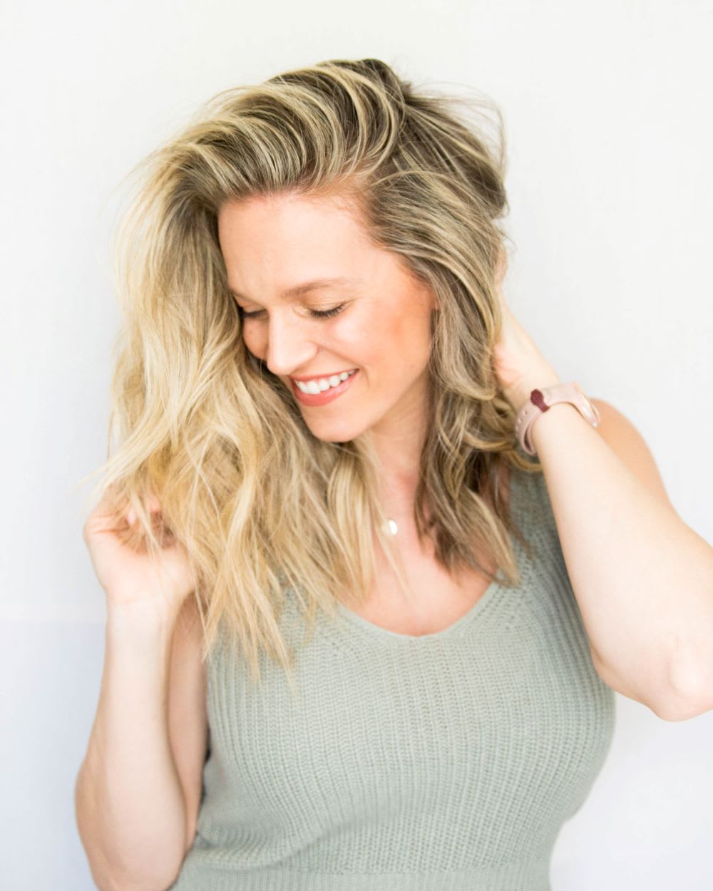 woman with side parted flat iron waves smiling and looking down