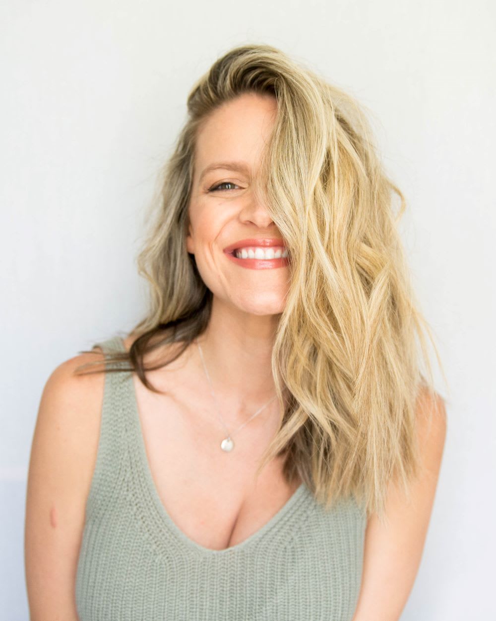 woman with blonde waves in green knit tank