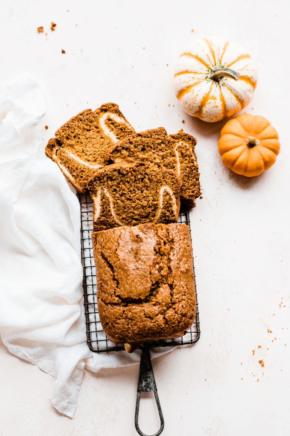 slices of pumpkin bread with cream cheese filling on a baking tray next to gourds
