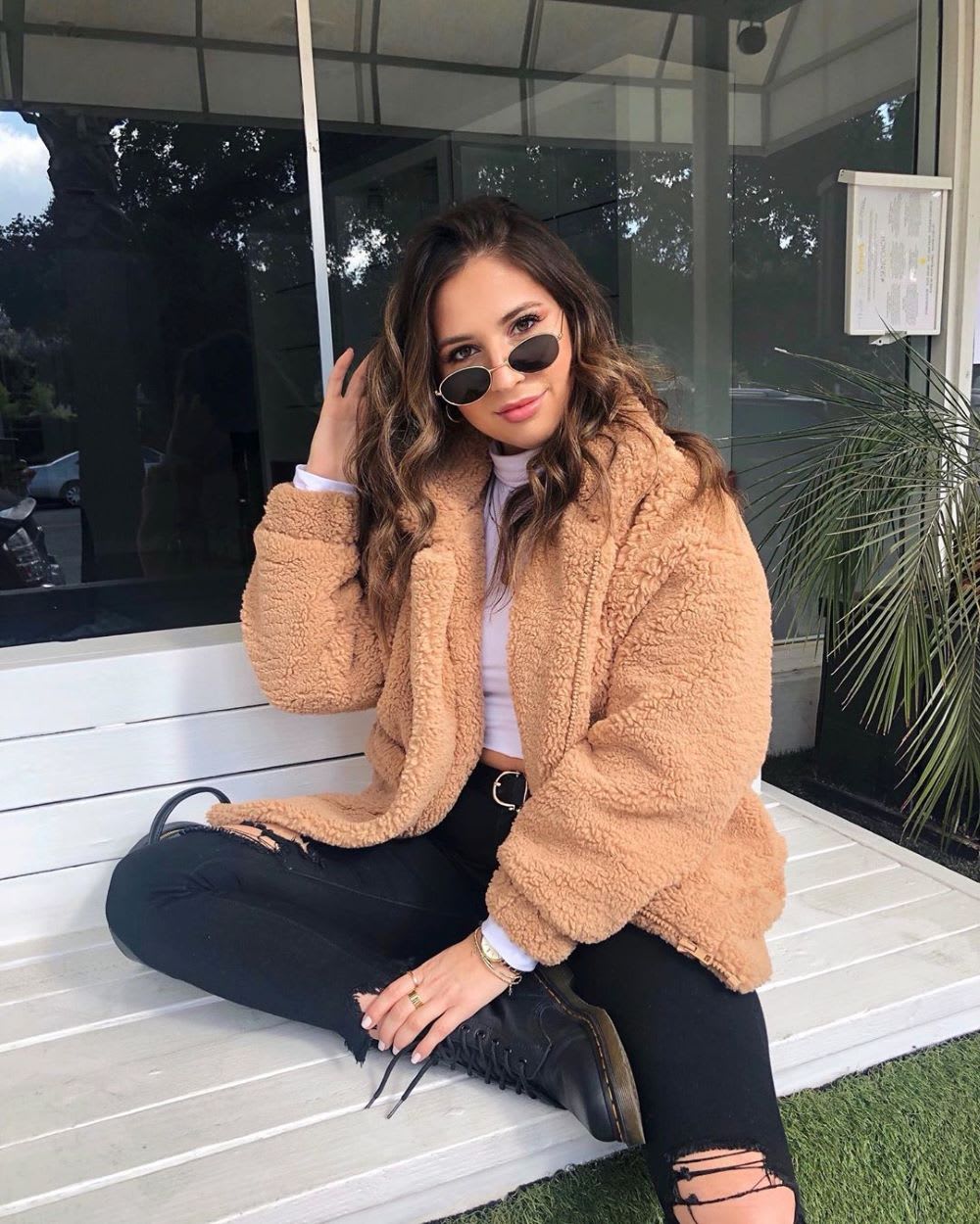 woman in a tan teddy coat with sunglasses and wavy chocolate chai fall hair color