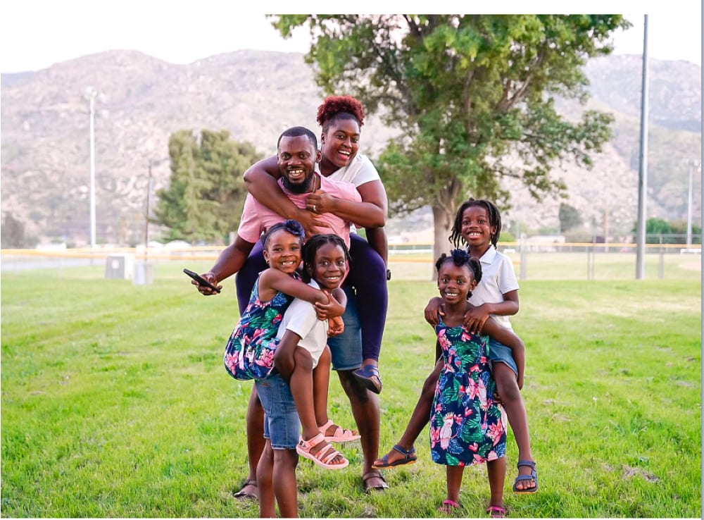 black family smiling and doing piggy back rides
