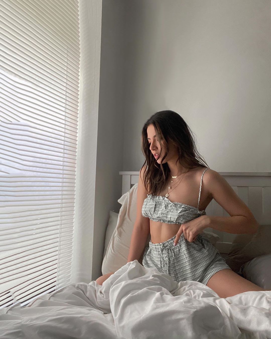 woman sitting in bed in gingham matching set: crisis fatigue symptoms and coping tips