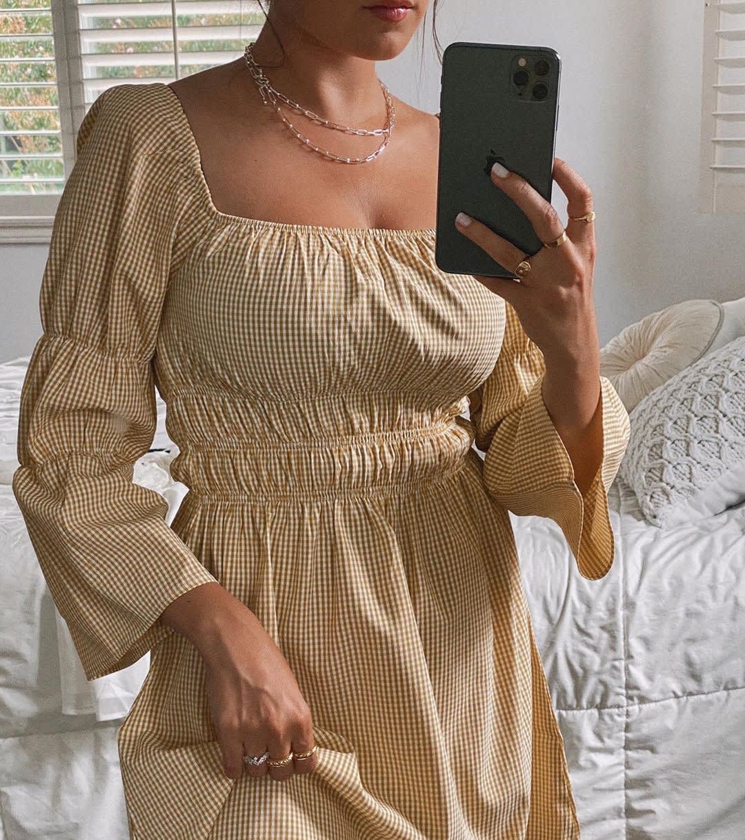 woman maintaining social connection via phone wearing a yellow gingham dress