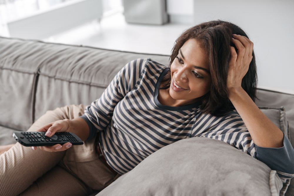 woman watching diverse tv shows on the couch at home