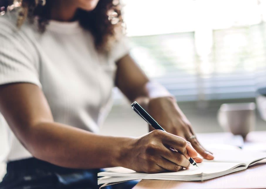 woman sitting writing financial budget in a notebook