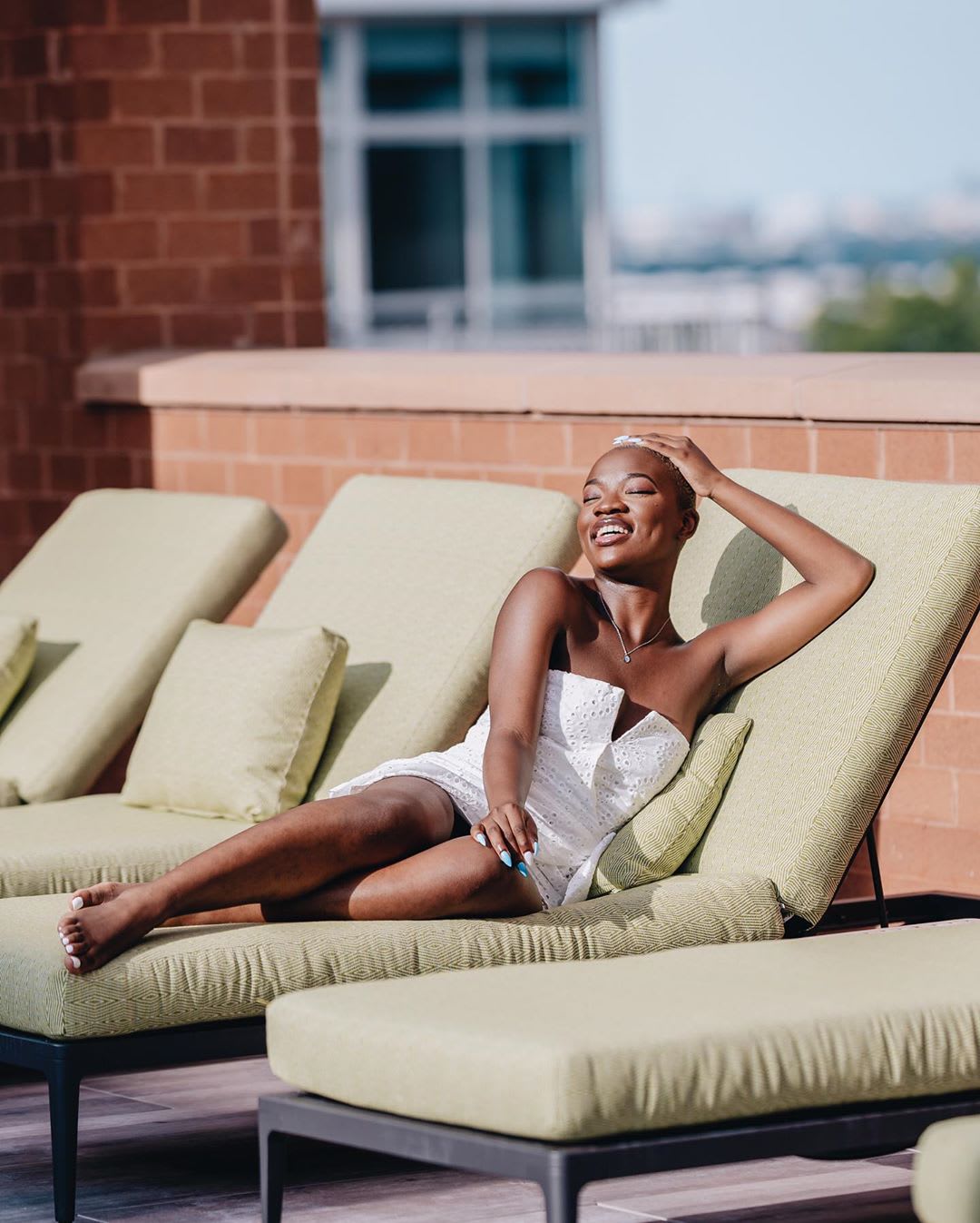 woman in a white mini dress on a lounge chair outside