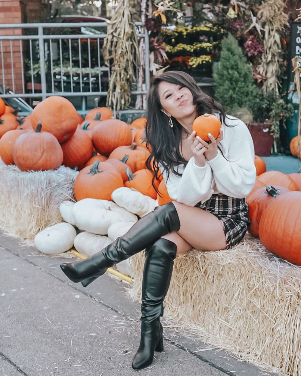 woman in a sweater and skirt with boots in a pumpkin patch for halloween