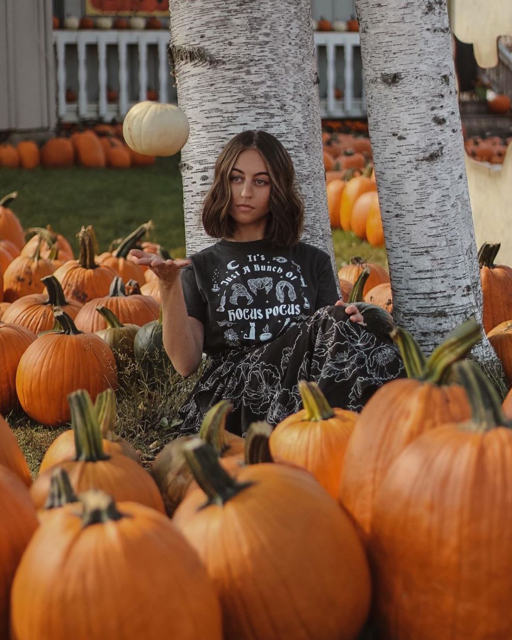 woman in a pumpkin patch wearing hocus pocus t-shirt and floral dress for halloween movies list