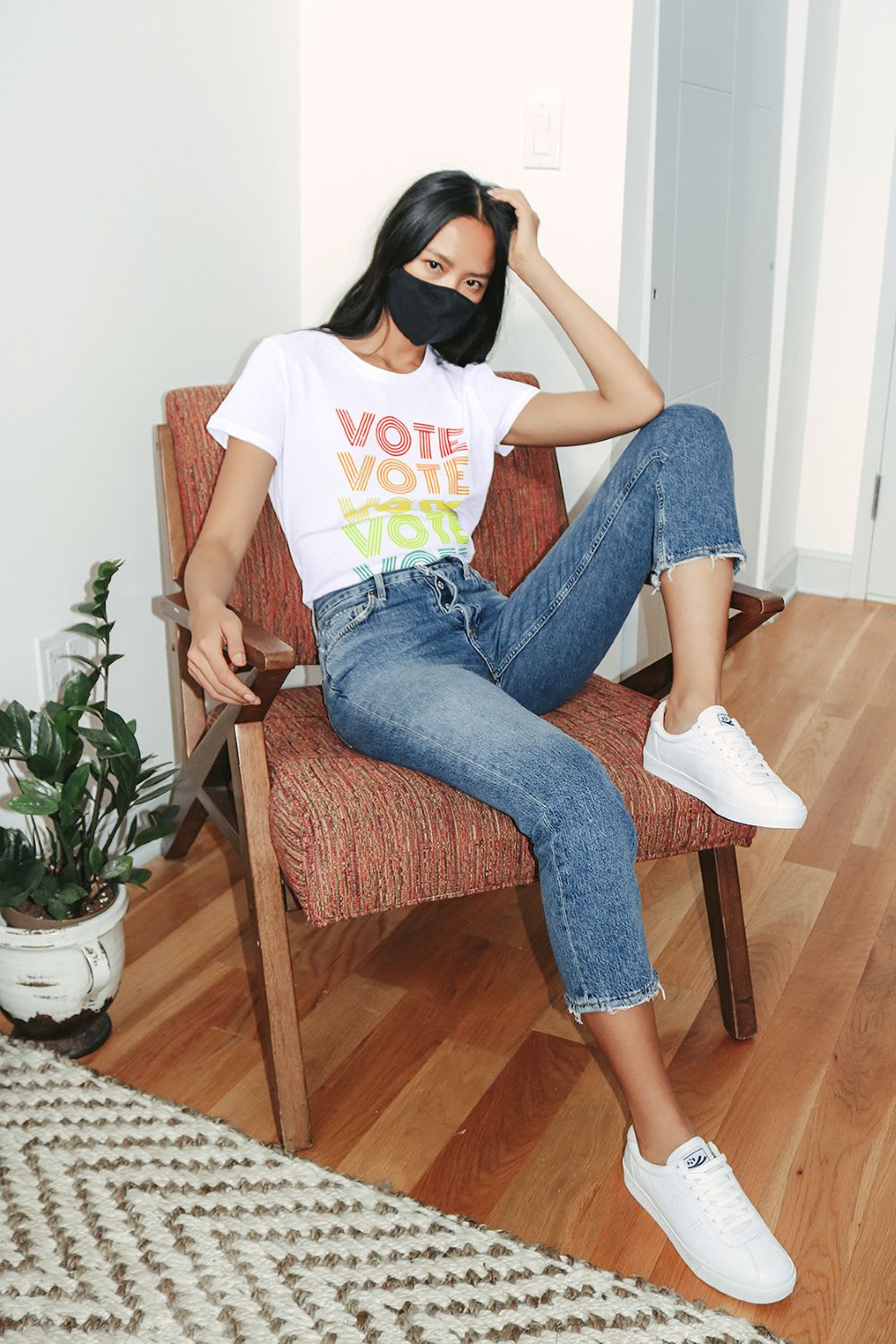 woman in jeans, a mask, and rainbow version of lulus vote t-shirts