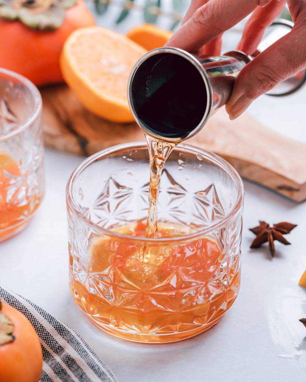 pouring into a glass for a persimmon whiskey cocktail 