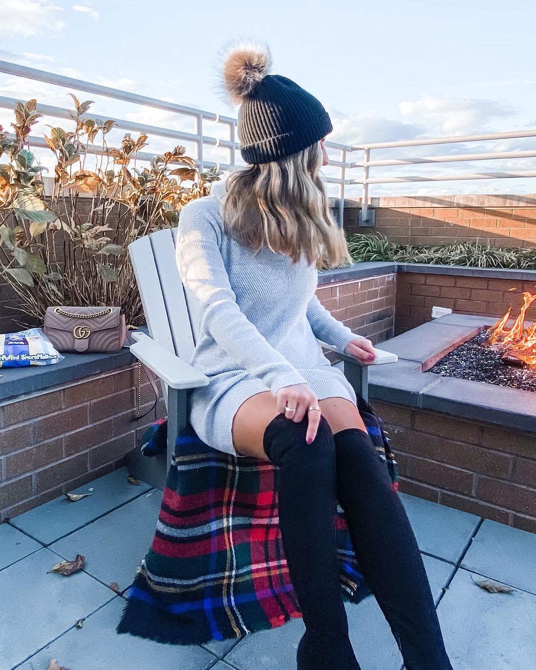 woman wearing a sweater dress with boots eating smores outdoors