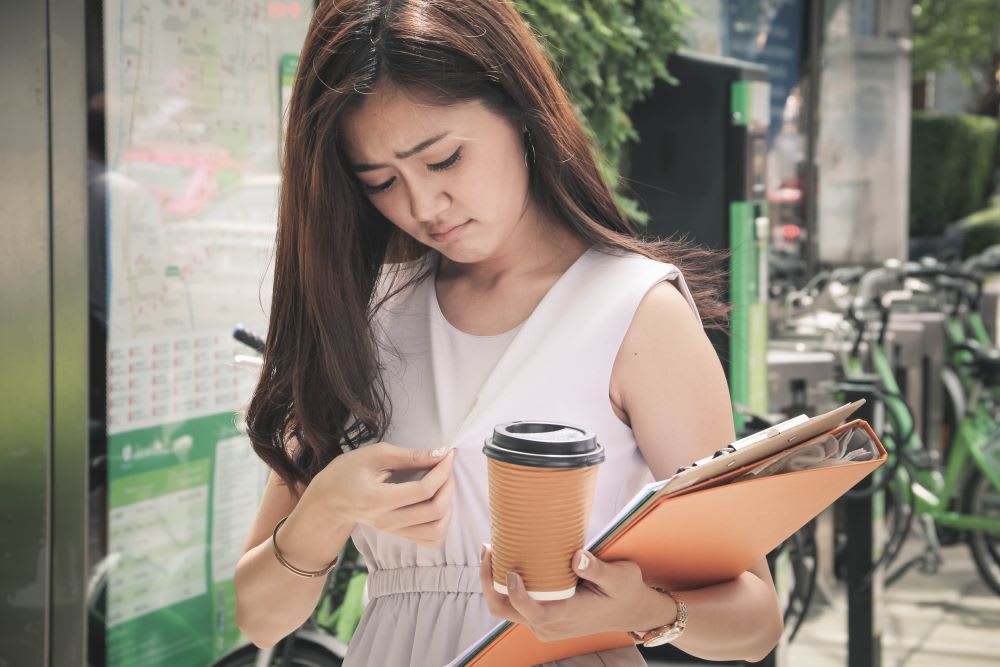 woman looking at coffee stain on her clothes