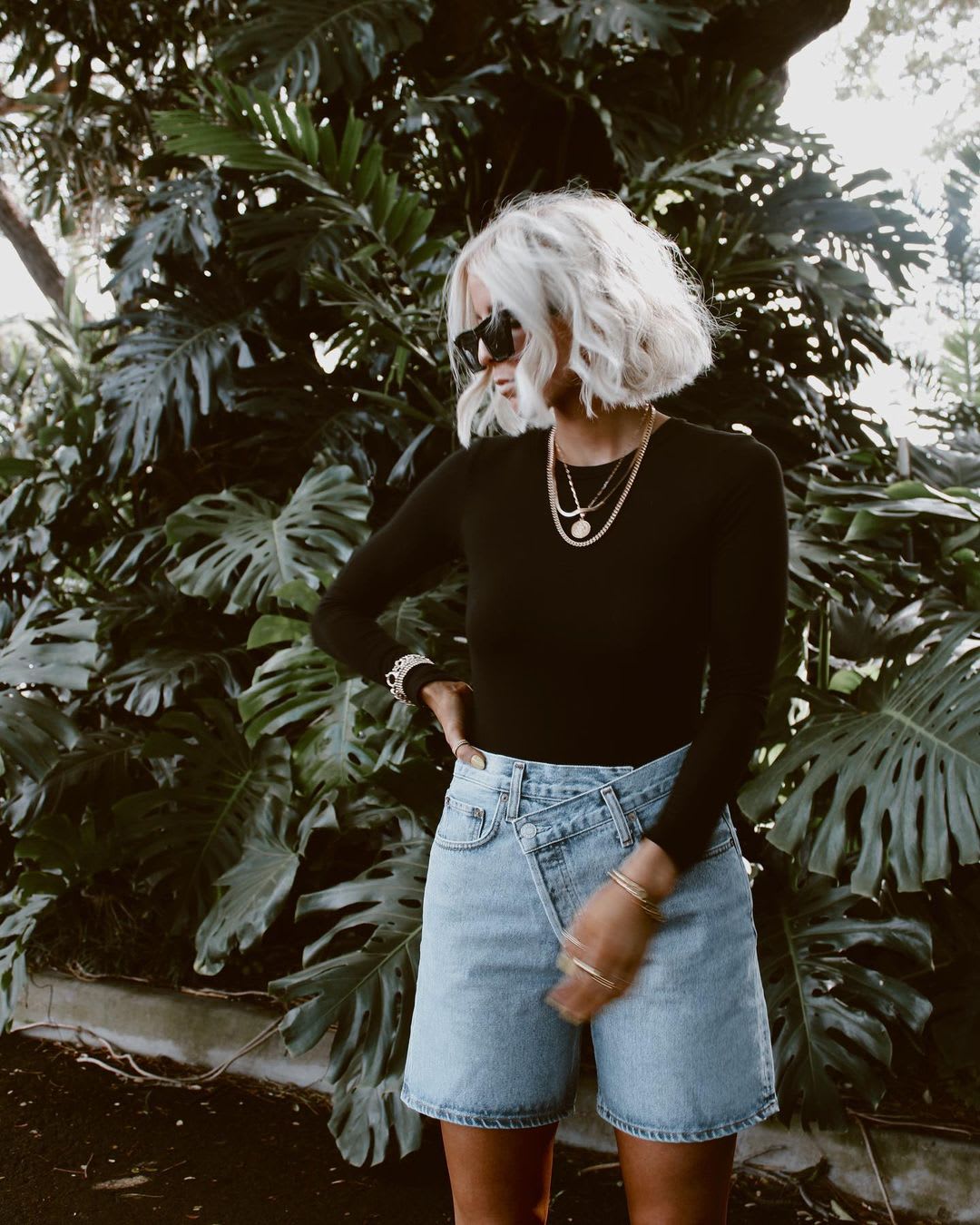 a woman in a '90s style outfit with black bodysuit and high rise denim shorts