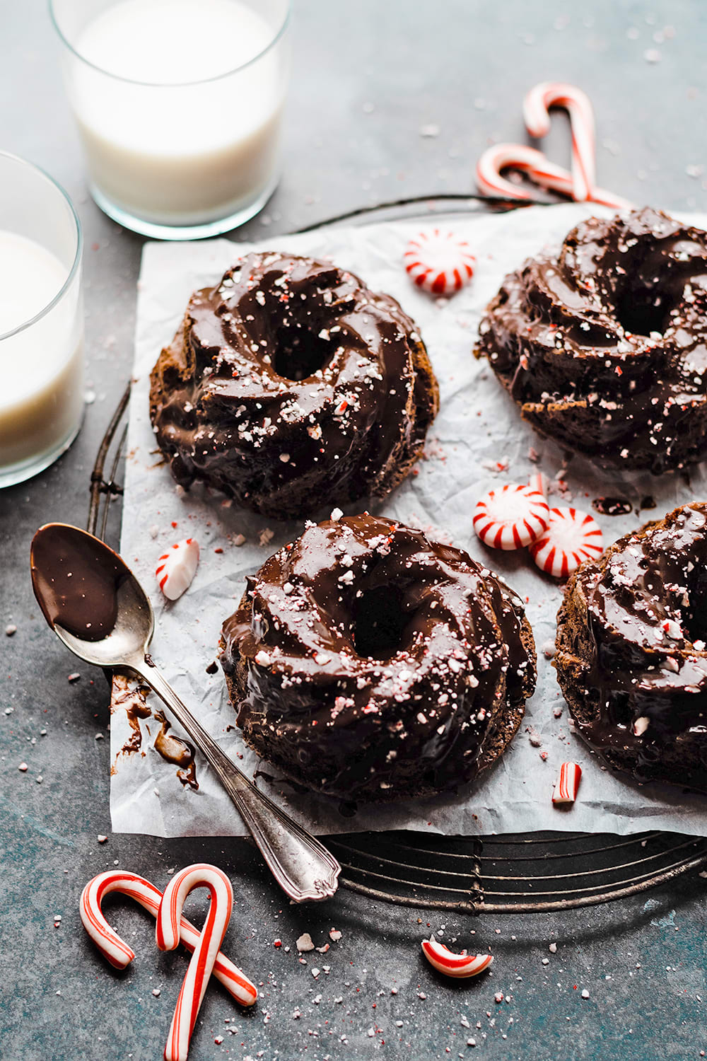 chocolate mini bundt cakes with peppermint topping and candy canes and glasses of milk