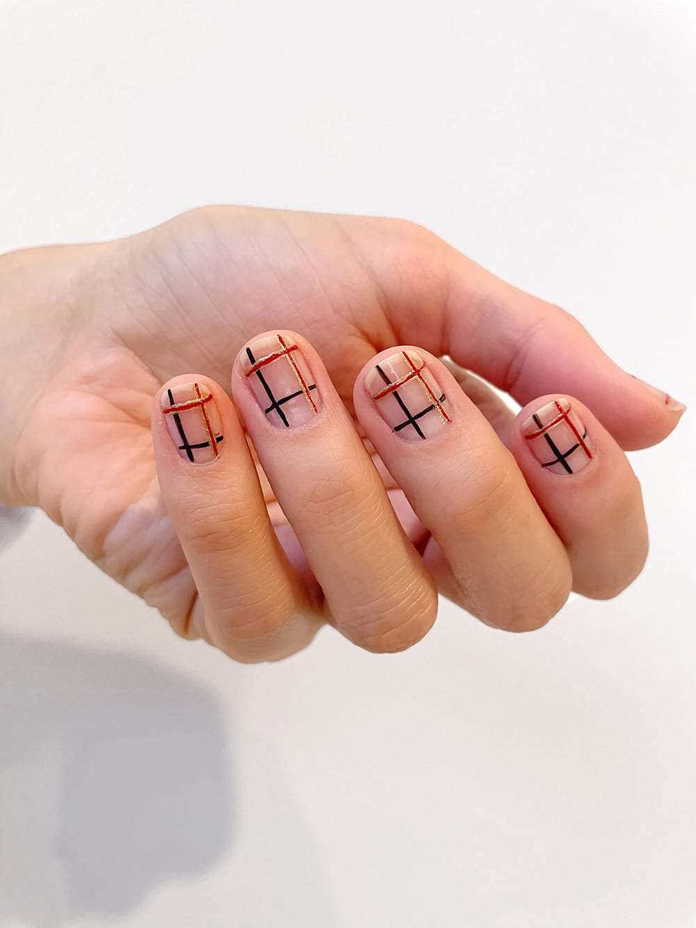 step 8 of plaid nails tutorial with red, gold and black lines