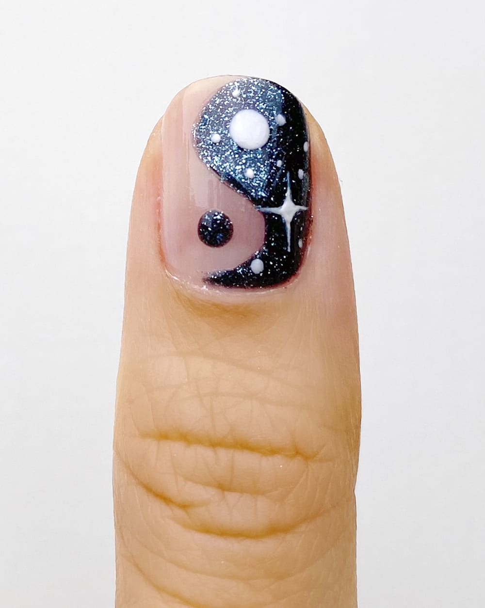 adding sparkly star design to dark blue yin yang nail design