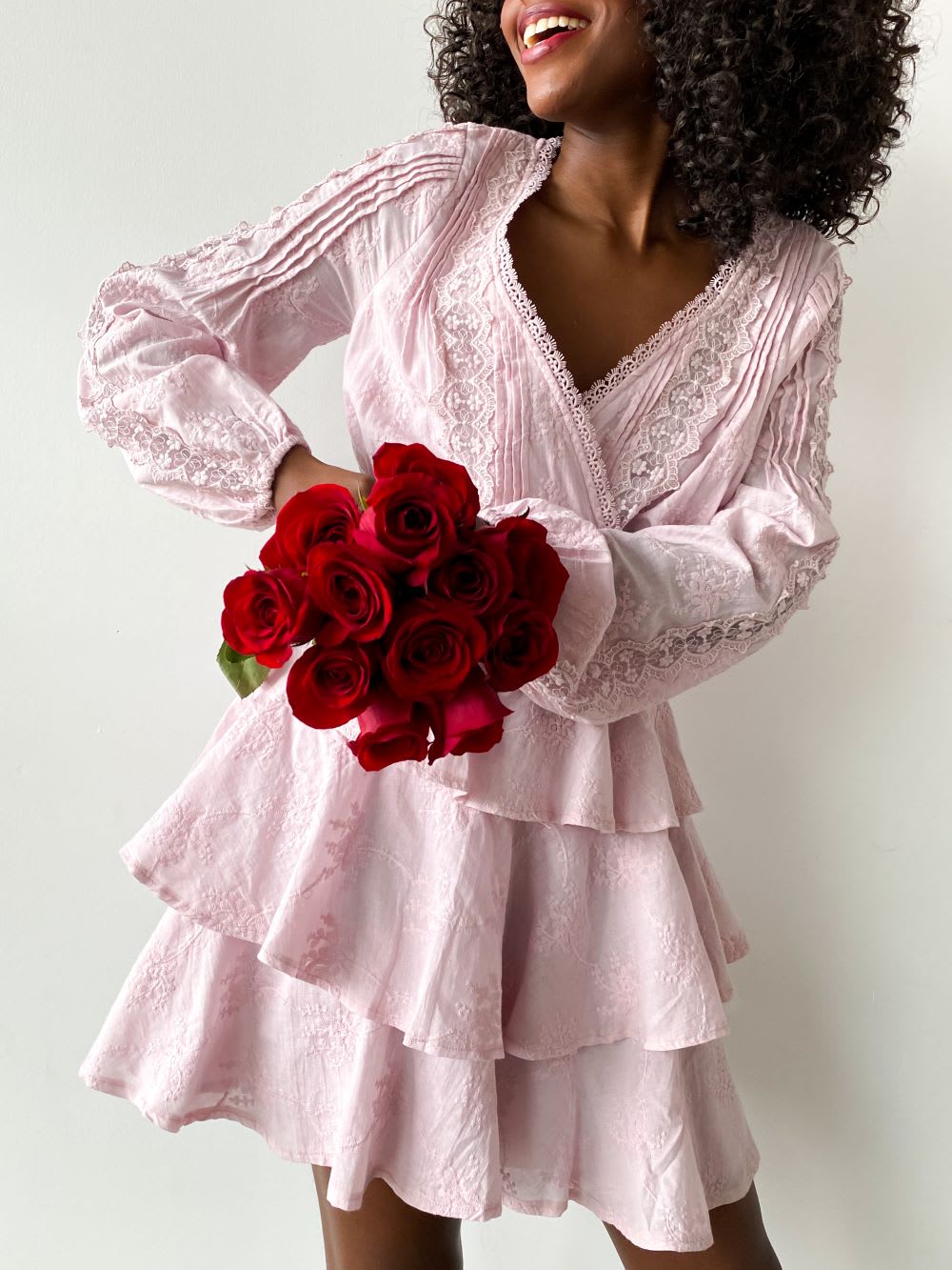 a woman wearing a pink ruffled Valentines dress and holding roses