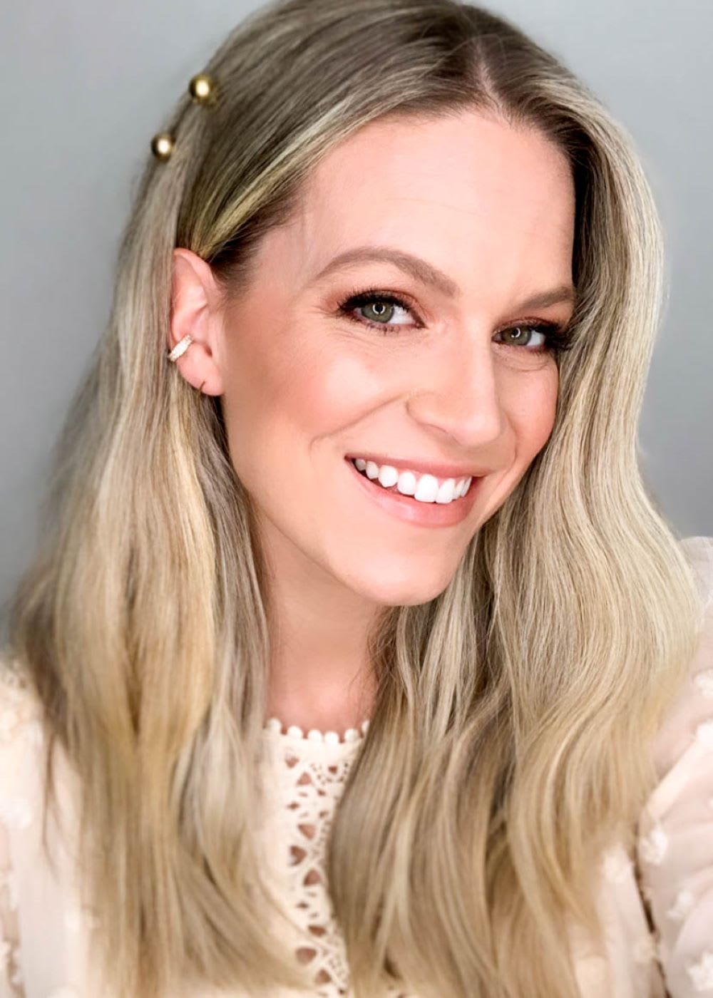 a blonde woman smilng with pins in her boho hairstyle and an ear cuff