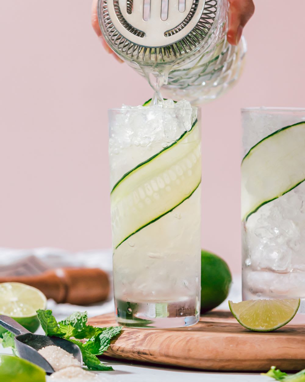 cucumber mojito being poured into glass with ice