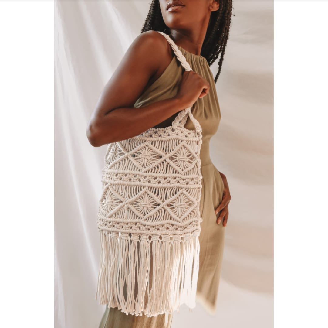 a woman carrying a cream macrame fringe tote