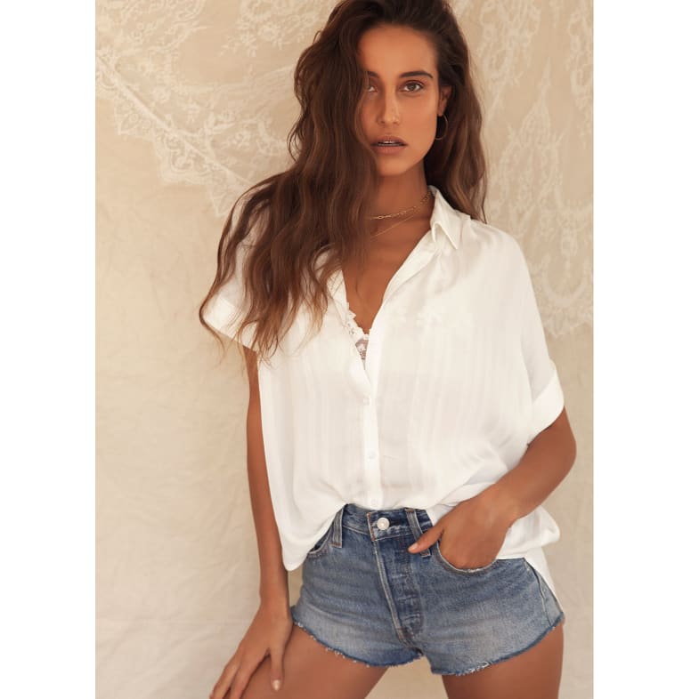 a woman wearing denim cutoffs and a white button up shirt