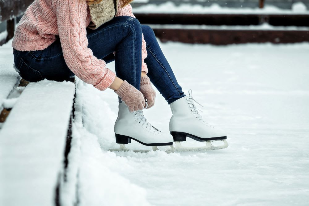 ands tying ice skates on rink for outdoor winter activities