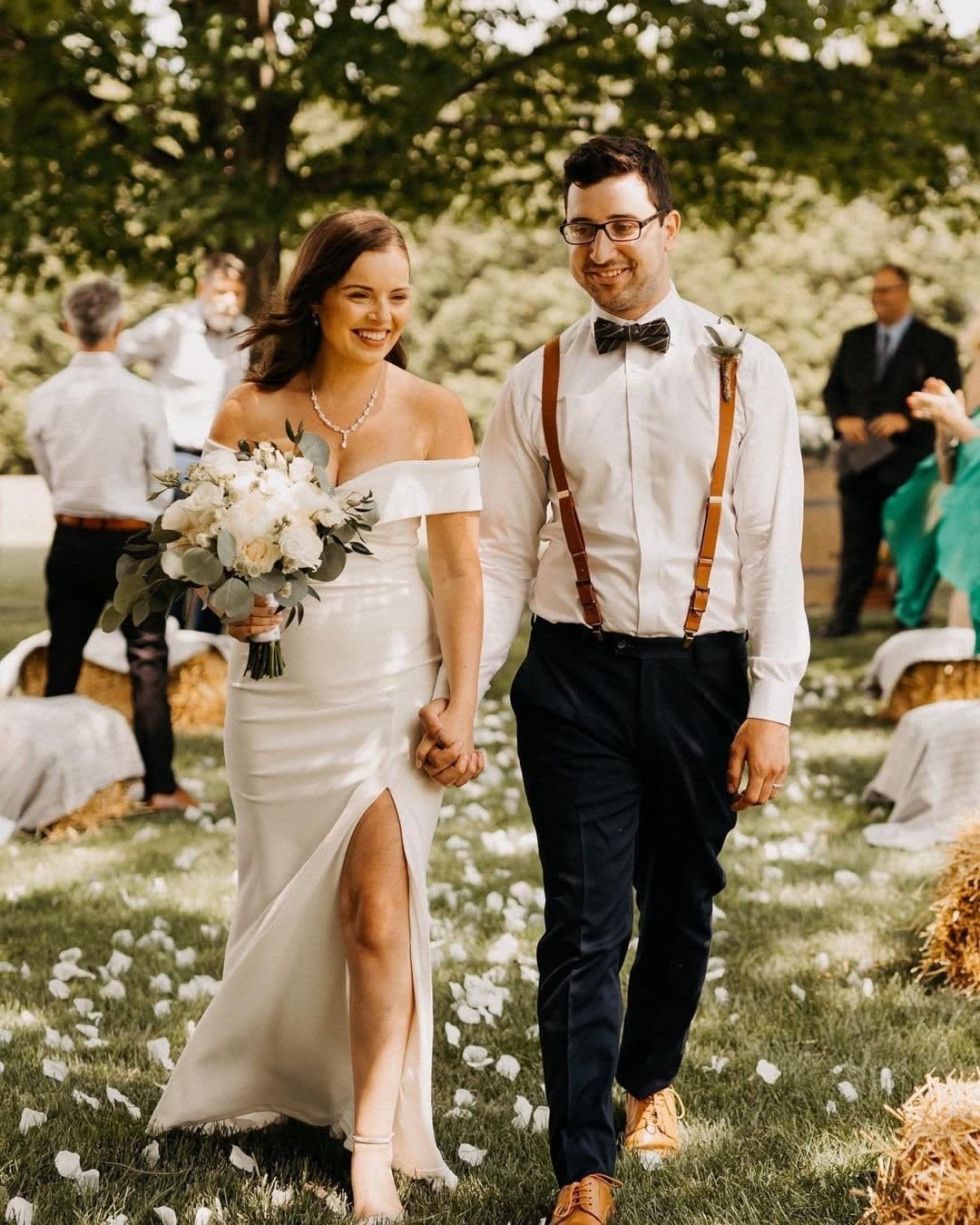 a couple walks down the aisle at a backyard wedding with hay bales
