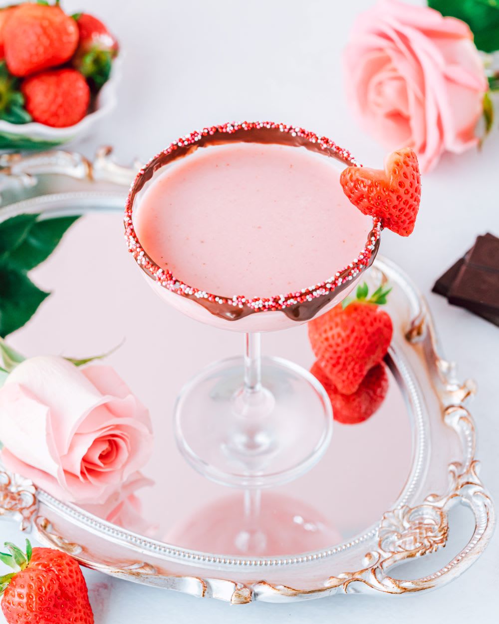pink strawberry and white chocolate liqueur cocktail with roses and strawberries on a tray for Valentine's Day